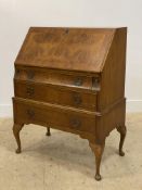 A 1930's walnut bureau with fall front opening to a fitted interior, above three drawers and