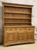 A polished pine dresser, fitted with a three height plate rack, above three drawers and three