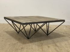 A contemporary coffee table, the hardwood top raised on four wrought metal pylon style supports.