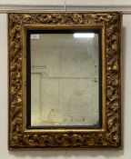 An early 20th century floral moulded gilt composition framed wall hanging mirror. 54cm x 67cm.