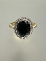 An 18ct gold sapphire and diamond cluster ring, the oval sapphire approximately 1.5ct in claw