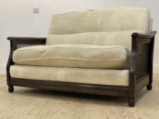 Ercol, a Vintage stained ash two seat sofa, with bergere side panels and white plush upholstered
