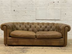 A traditional chesterfield sofa, upholstered in deep buttoned tan leather and crushed velvet sides