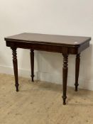 A Victorian mahogany tea table, the fold over revolving top raised on turned and tapered supports.