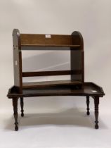 An early 20th century oak tabletop book trough with open shelf under, raised on arched panel end