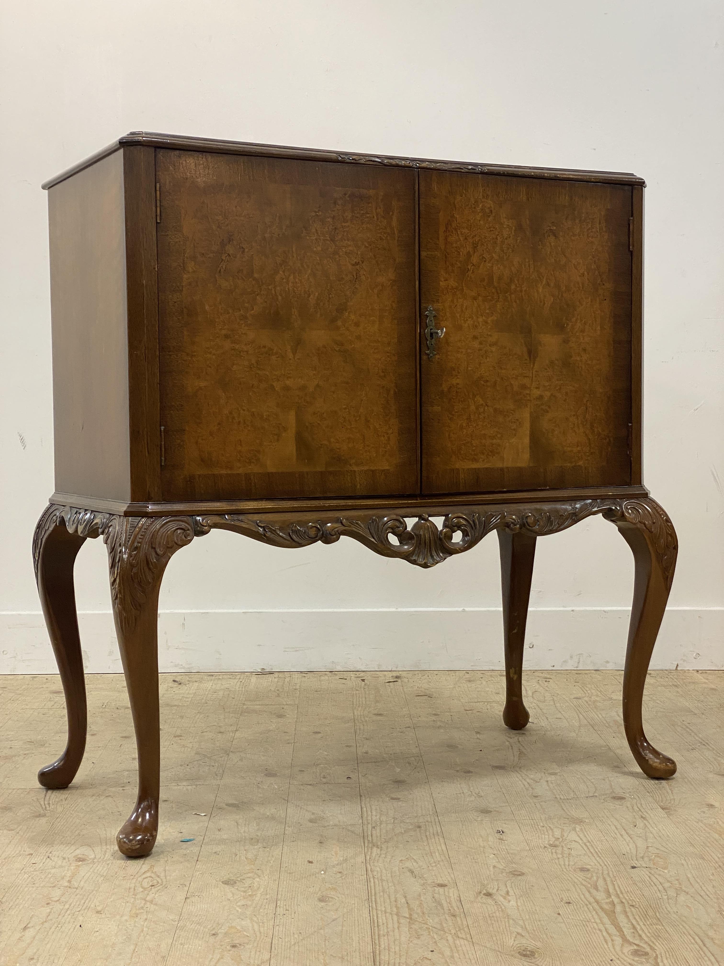 A mid 20th century burr walnut cocktail cabinet in the Georgian taste, plate glass top over two