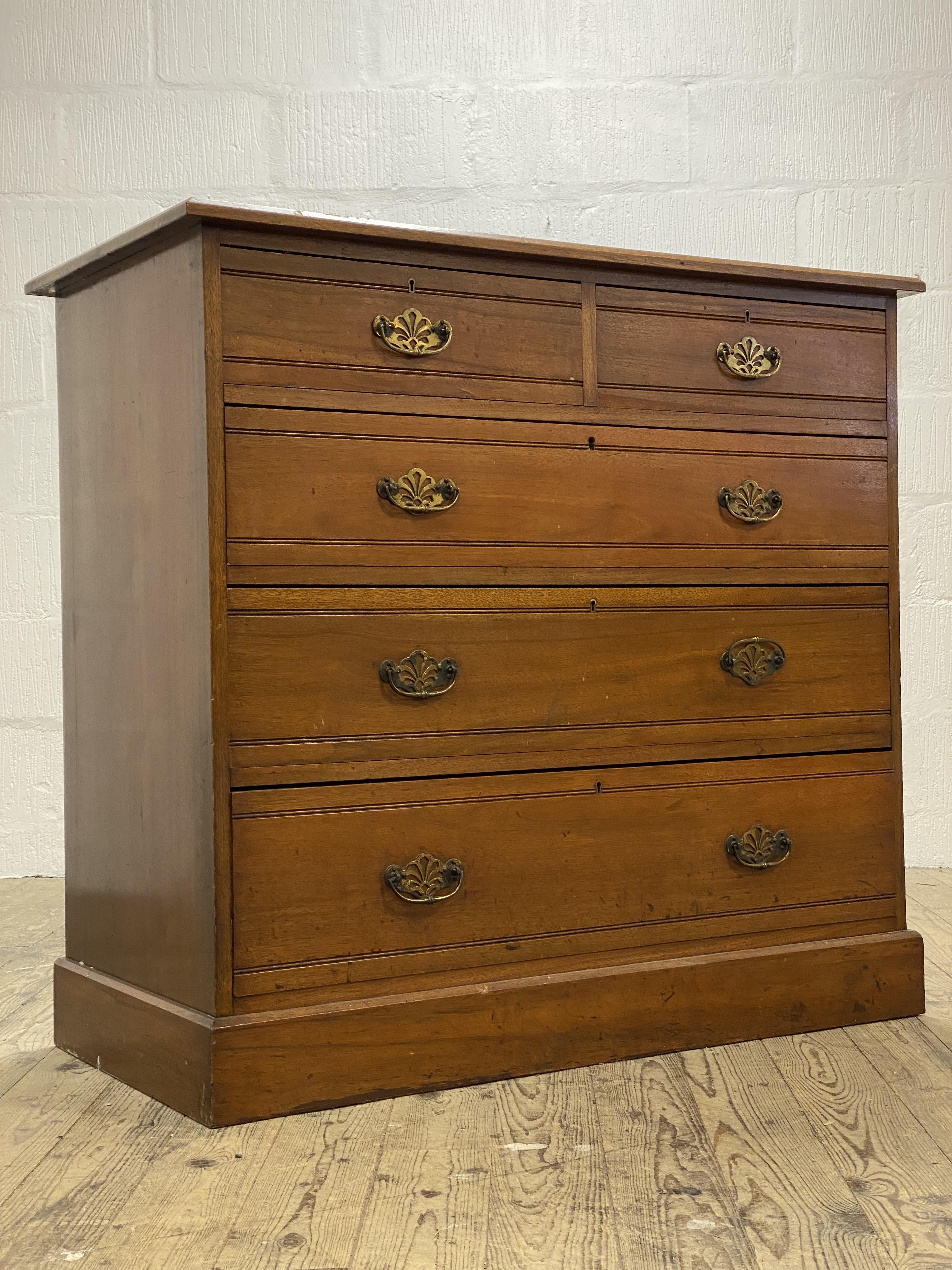 An Edwardian walnut chest of two short and three long graduated drawers, raised on a plinth base.