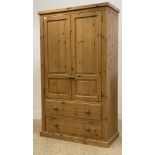 A polished pine two door wardrobe, the interior fitted for hanging and with two drawers to base.