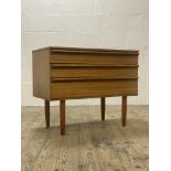 A mid century teak chest, fitted with three drawers and standing on turned and tapered supports.