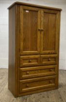A Canadian oak tall boy, a pair of panelled doors enclosing a shelf and a drawer, above two short