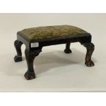 An early 20th century stained mahogany footstool with drop in upholstered seat pad raised on