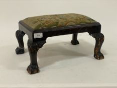 An early 20th century stained mahogany footstool with drop in upholstered seat pad raised on