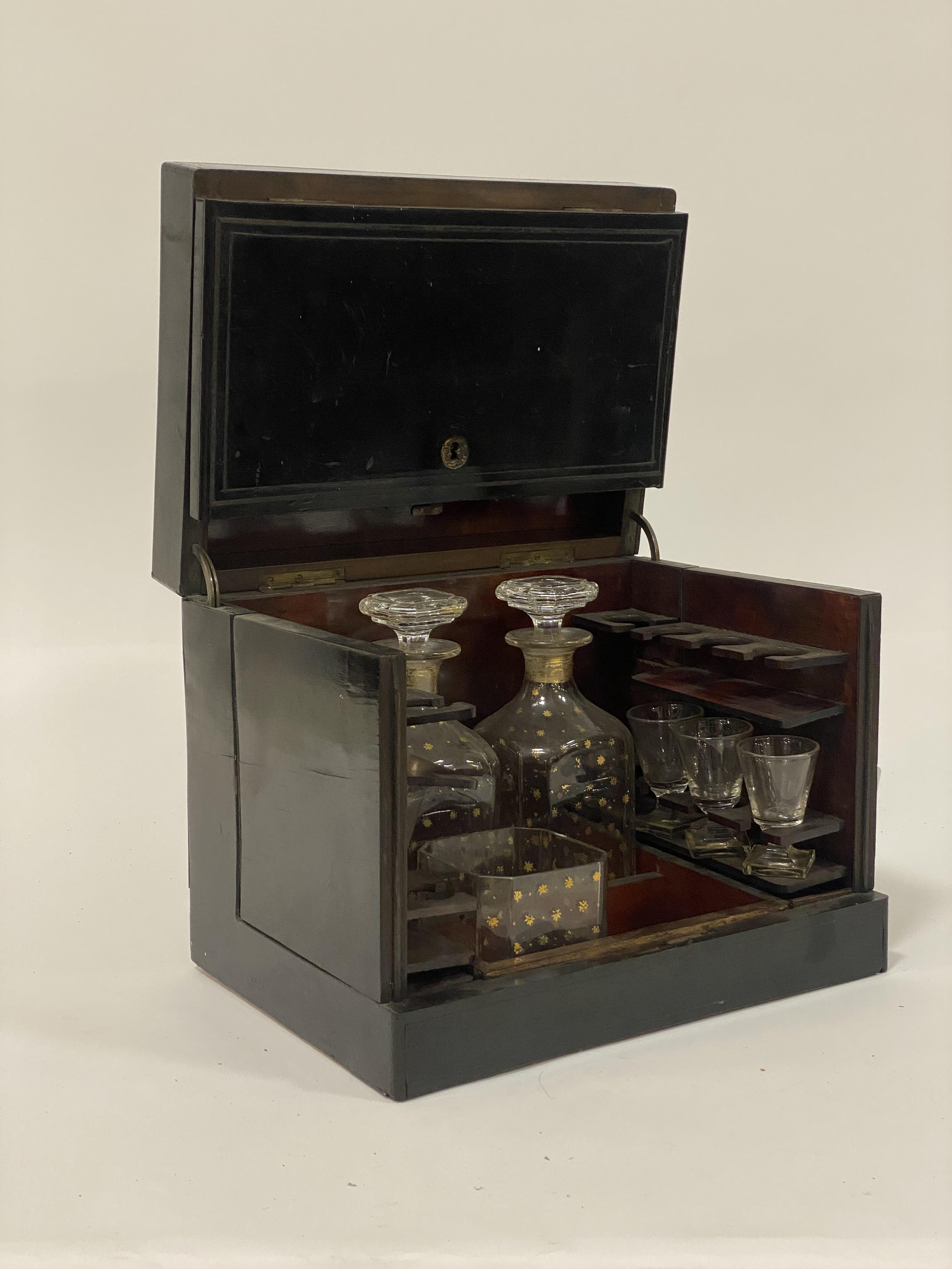 A mid19th century ebonised tantalus or drinks casket, the hinged lid enclosing a simulated