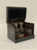A mid19th century ebonised tantalus or drinks casket, the hinged lid enclosing a simulated
