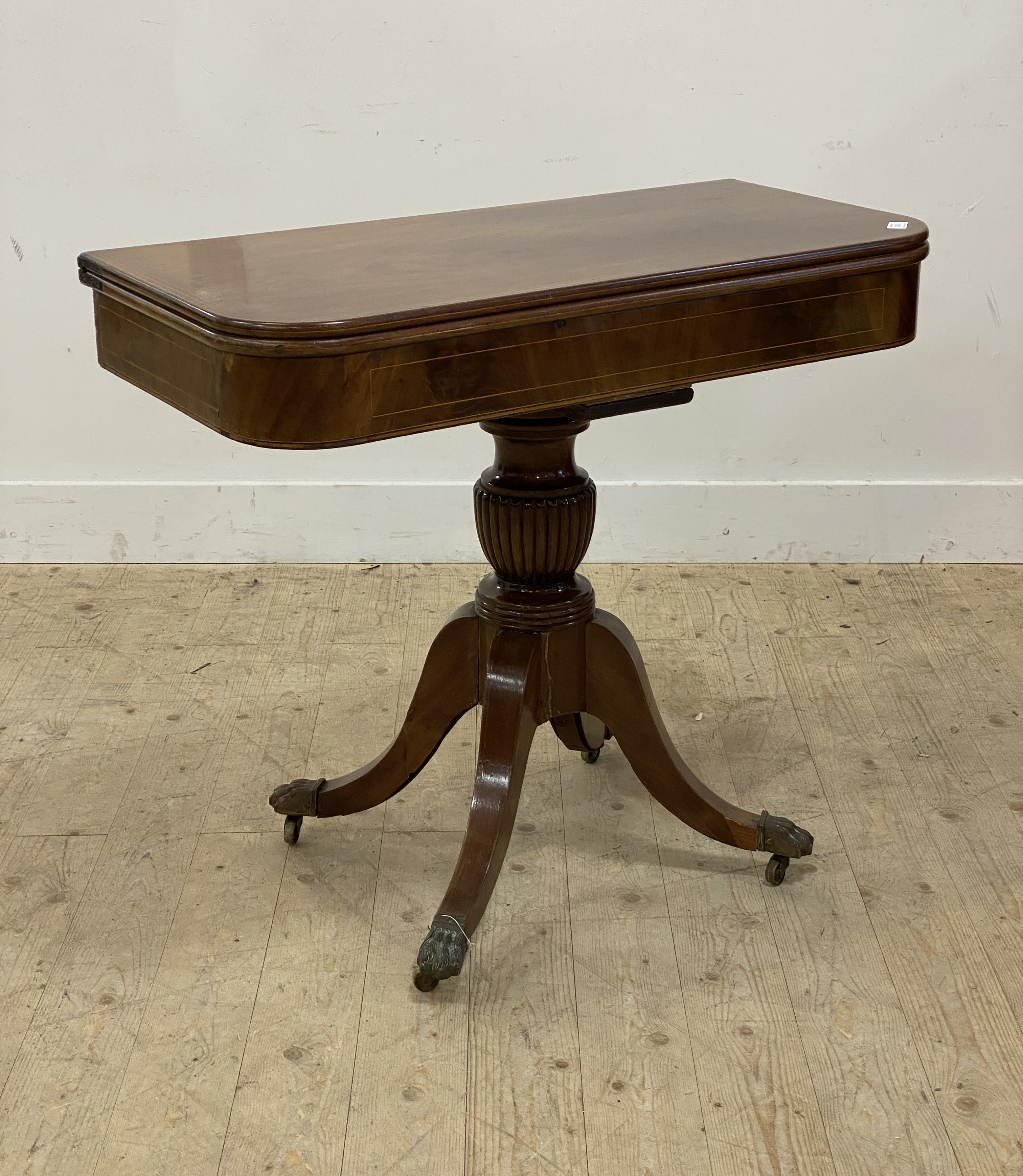 A Regency mahogany fold over tea table, the boxwood string inlaid top raised on four splayed