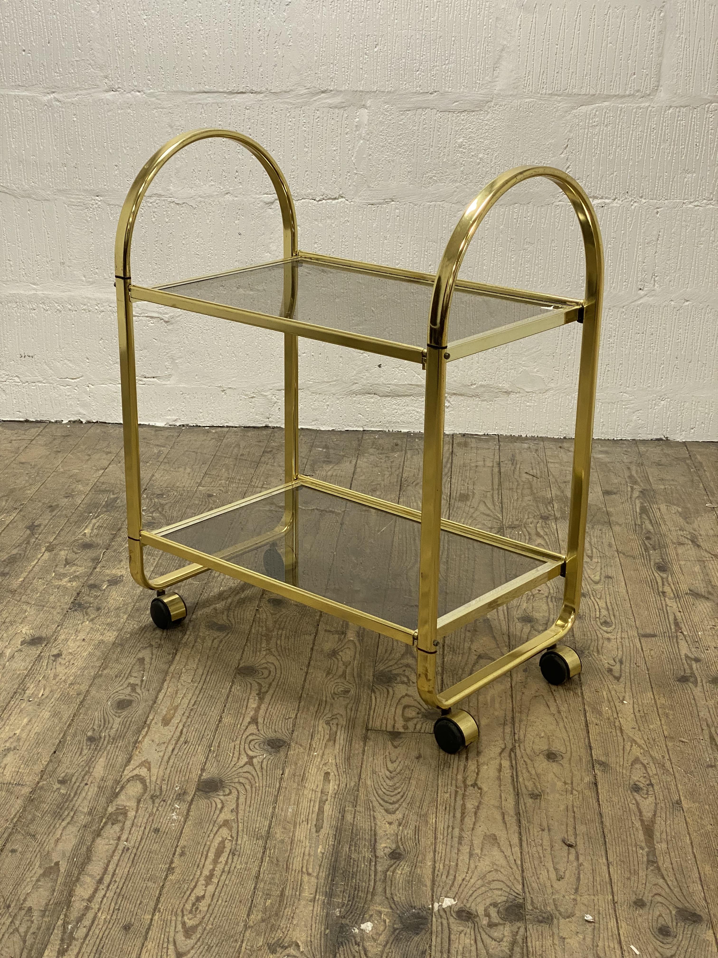 A Vintage 1980's two tier gilt metal and smoked glass drinks trolley, moving on castors. H85cm,