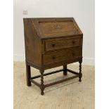 A 1930's oak bureau, the fall front opening to a fitted interior, above two drawers and raised on