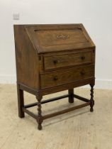 A 1930's oak bureau, the fall front opening to a fitted interior, above two drawers and raised on