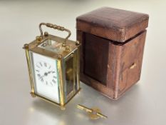 A Edwardian French brass four glass travelling clock with folding handle to top white enamel dial