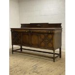 A 1930's oak sideboard, the raised back centred with cartouche above two drawers and two geometric