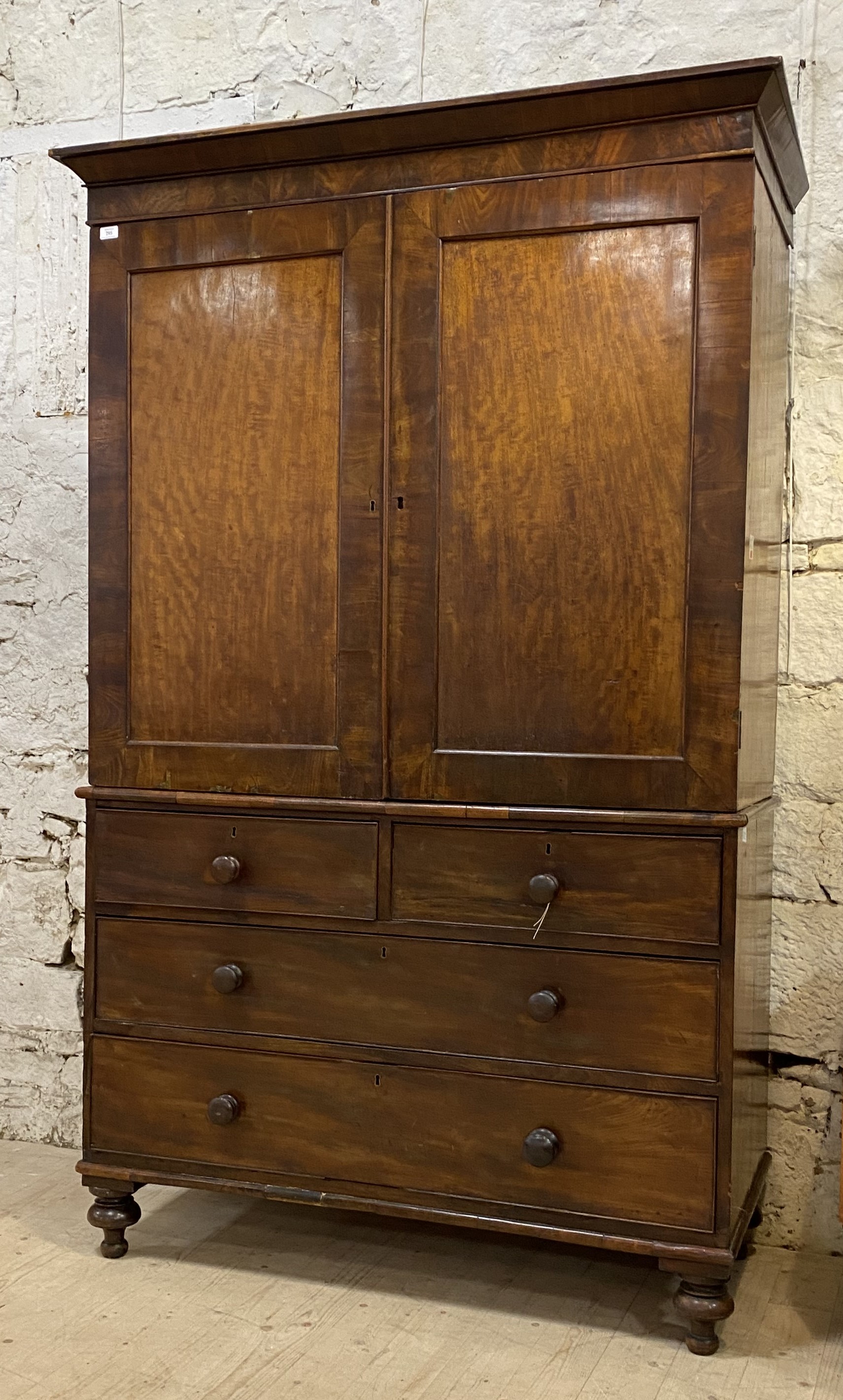 A George III mahogany linen press, the projecting cornice above two panelled doors enclosing three