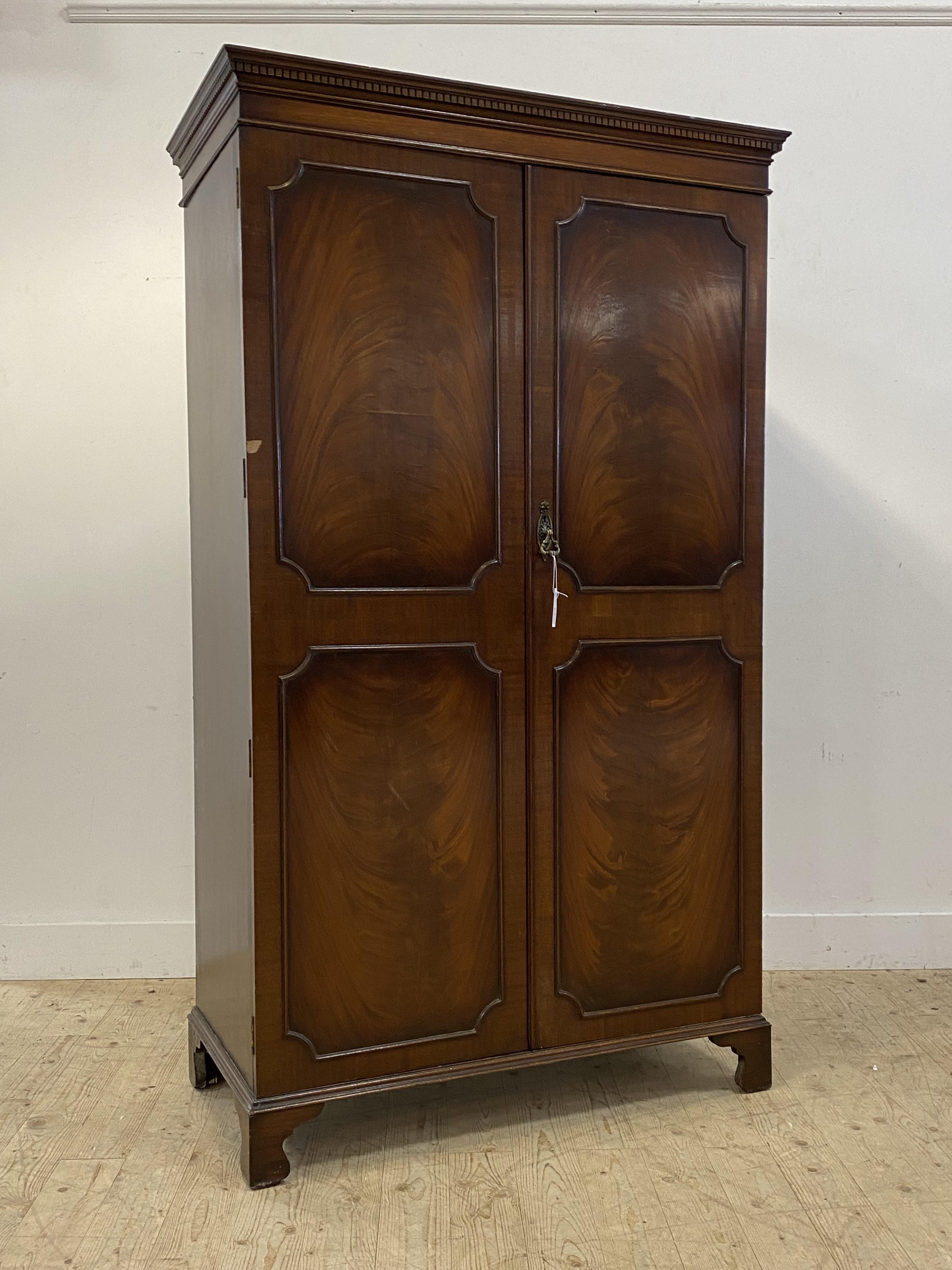 An early 20th century mahogany wardrobe, with dentil cornice over two twin panelled doors opening to