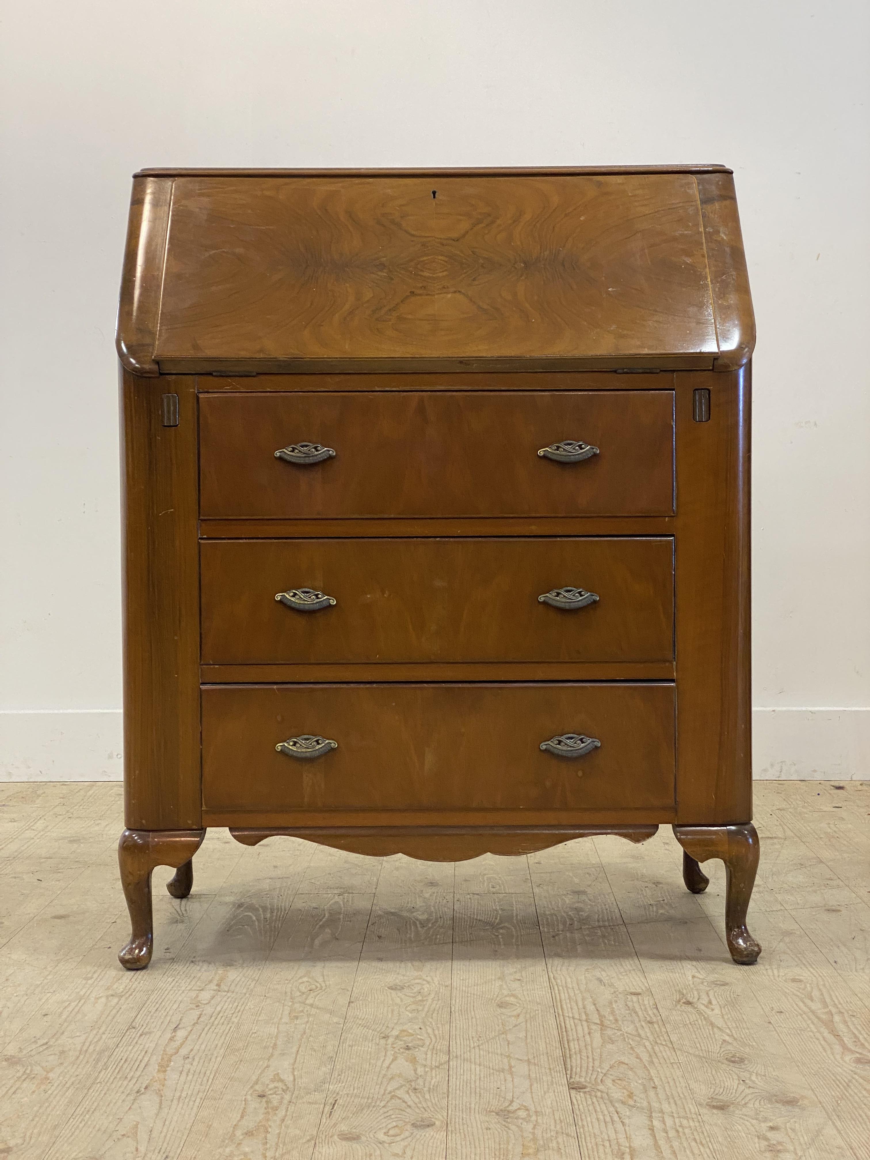 A 1930's walnut veneered bureau. the fall front opening to a fitted interior, above three drawers,