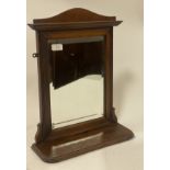 An Edwardian walnut framed wall hanging mirror, the arched top over reeded frame enclosing