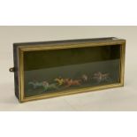 An ebonised and parcel gilt glazed display case enclosing seven early 20th century lead painted