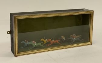 An ebonised and parcel gilt glazed display case enclosing seven early 20th century lead painted