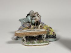 A Continental porcelain figure of a seated woman playing the piano while a man courts her. (loss/