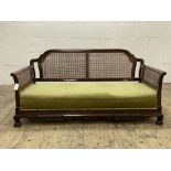 A 1920's walnut bergere sofa, with undulating back rail and cane panelled back and sides, raised