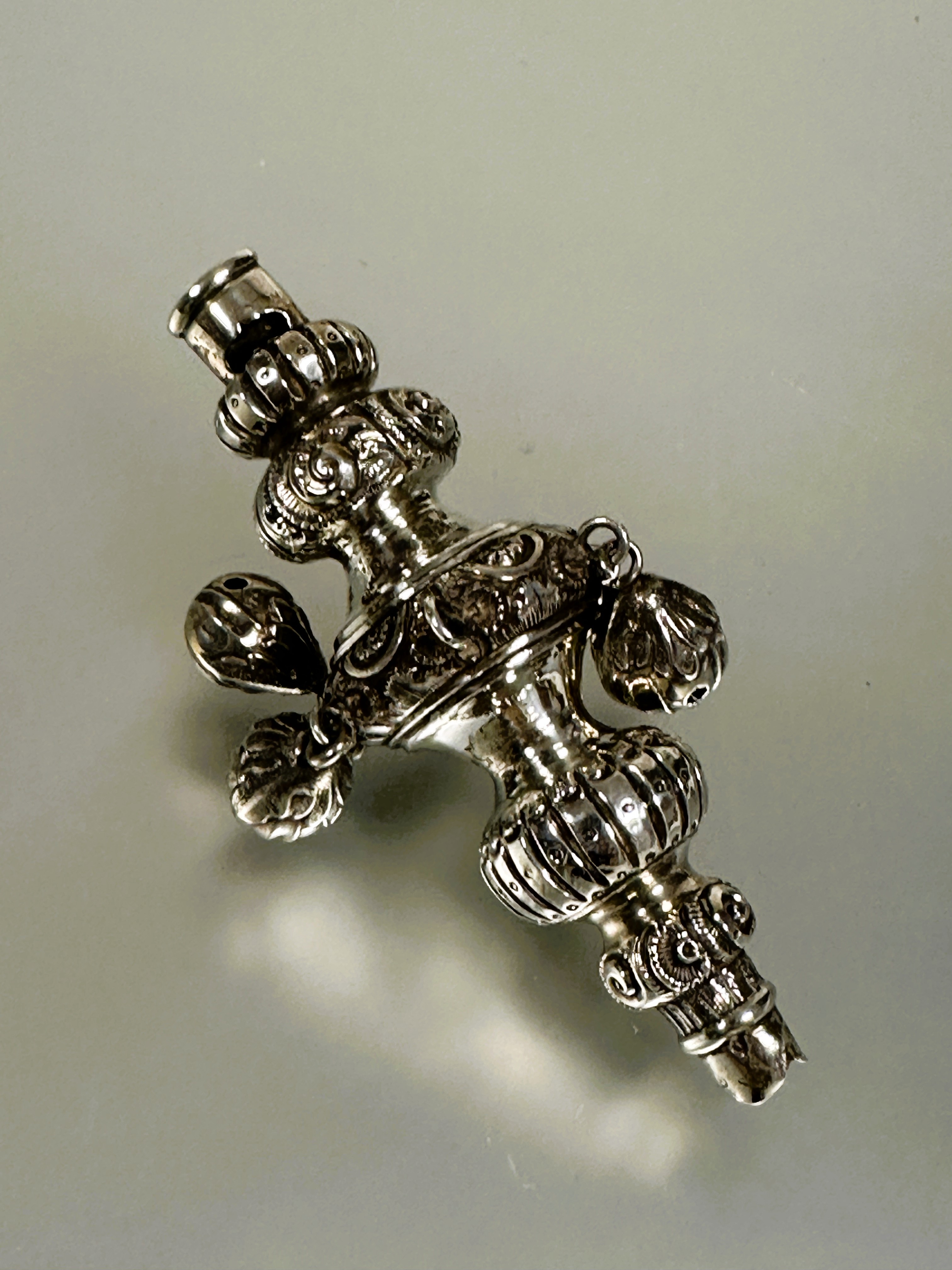 A 19thc white metal child's teething rattle/whistle of typical tiered form with cased scrolling