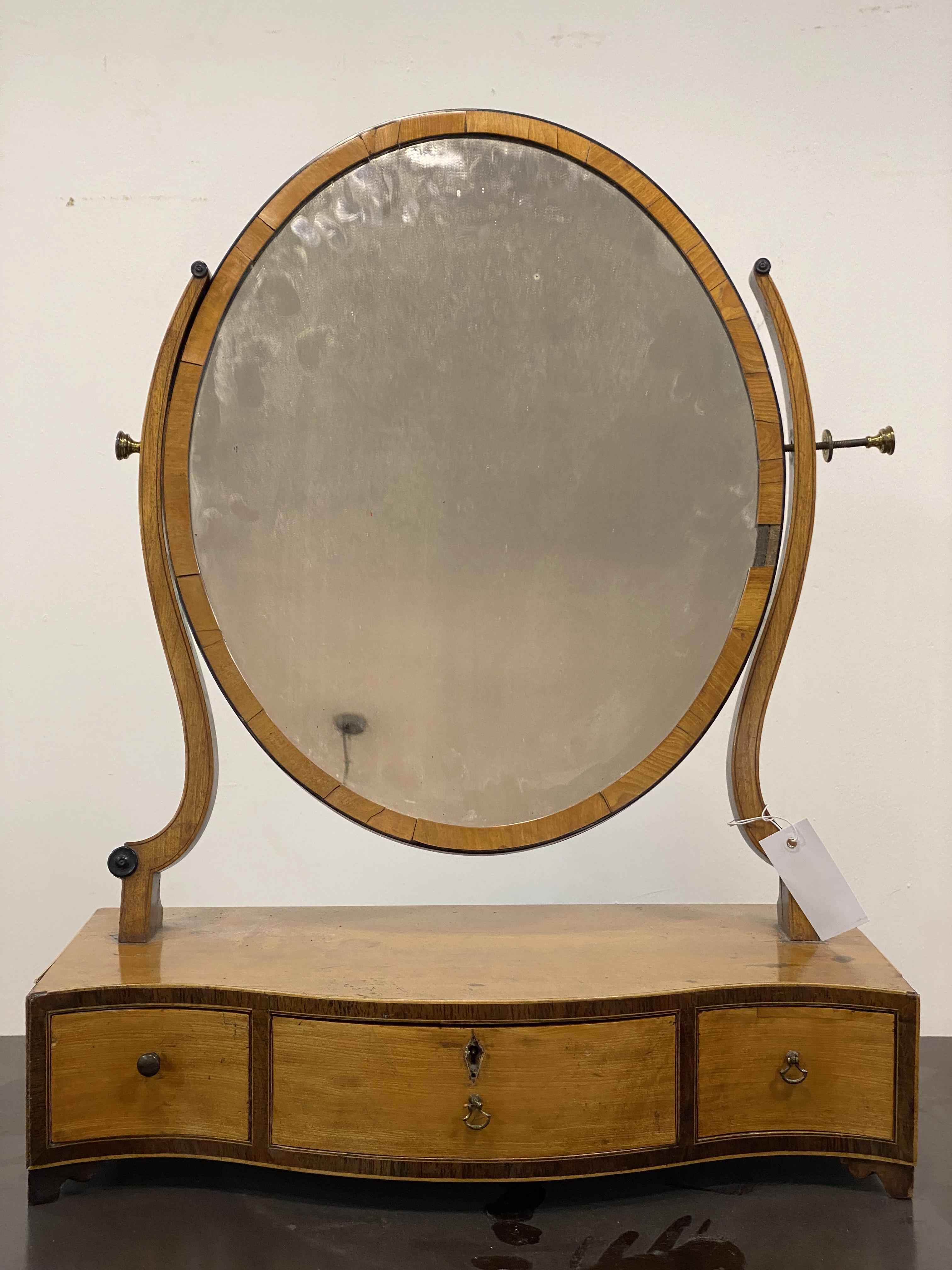 A Georgian satin birch toilet mirror, the oval plate swivelling between two scrolling uprights, with