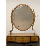 A Georgian satin birch toilet mirror, the oval plate swivelling between two scrolling uprights, with