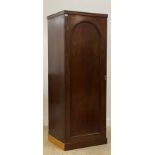 A Victorian mahogany cupboard, the arch panelled door opening to an interior fitted with three