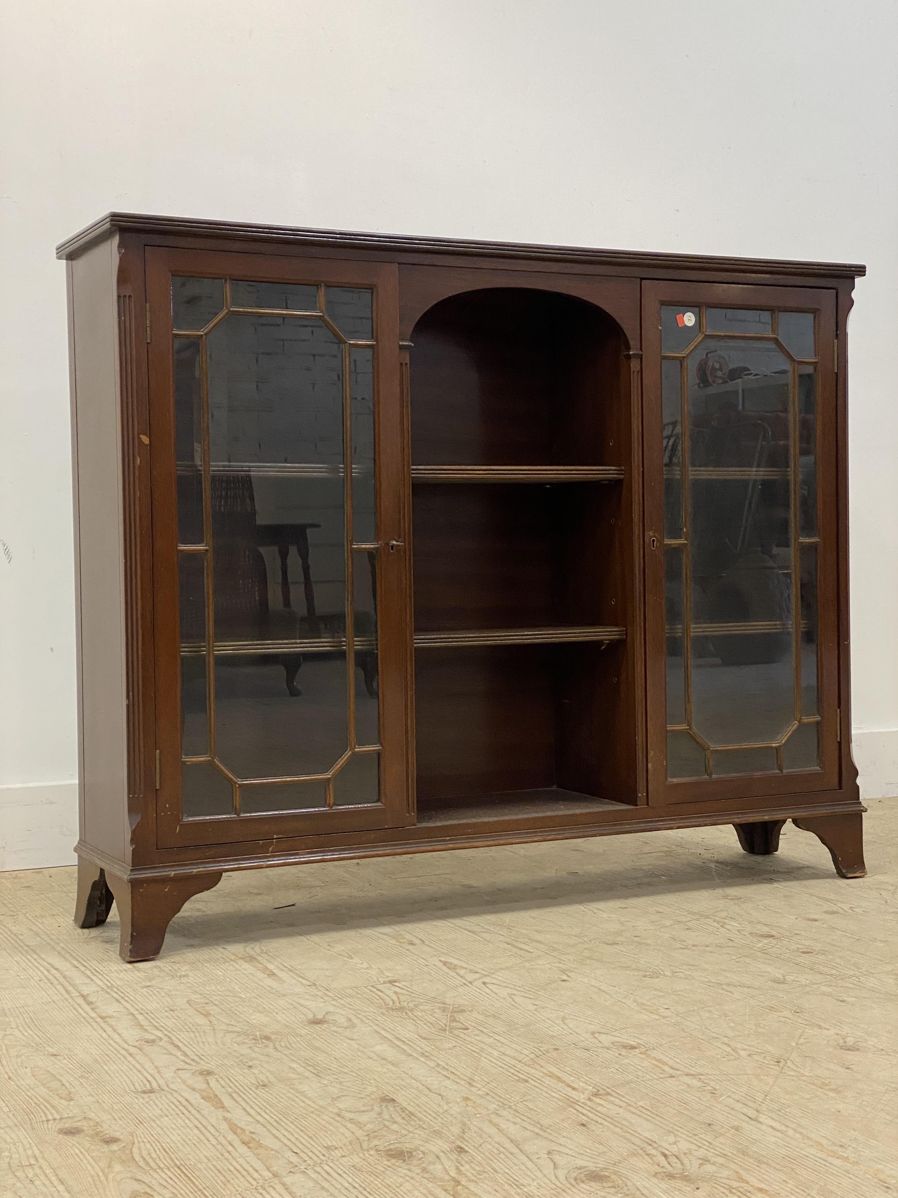 A mahogany bookcase cabinet, with canted and fluted corners enclosing two astragal glazed doors,
