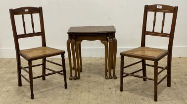 A pair of Edwardian walnut bedroom chairs, with spindle back rest and cane seats, raised on turned