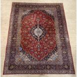 A hand knotted Persian Keshan rug, the red field centred with medallion and enclosed by conforming
