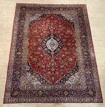 A hand knotted Persian Keshan rug, the red field centred with medallion and enclosed by conforming