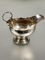 A Edwardian Chester silver milk jug of oval form with scalloped with C scroll handle raised on