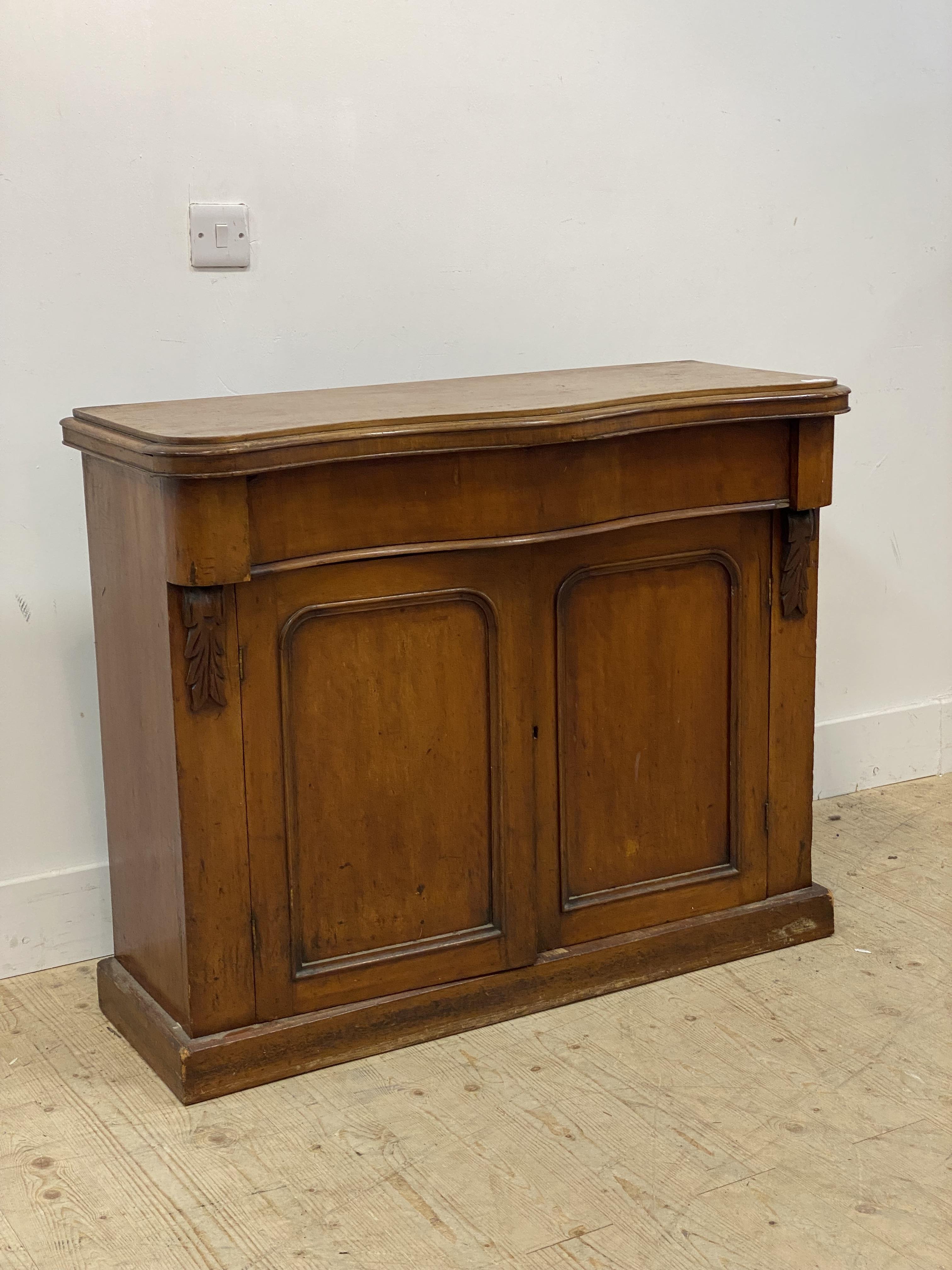 A Victorian mahogany side cabinet of serpentine outline, fitted with a frieze drawer, above two