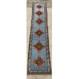 A hand knotted Turkish runner rug, the pale blue field decorated with six geometric medallions,