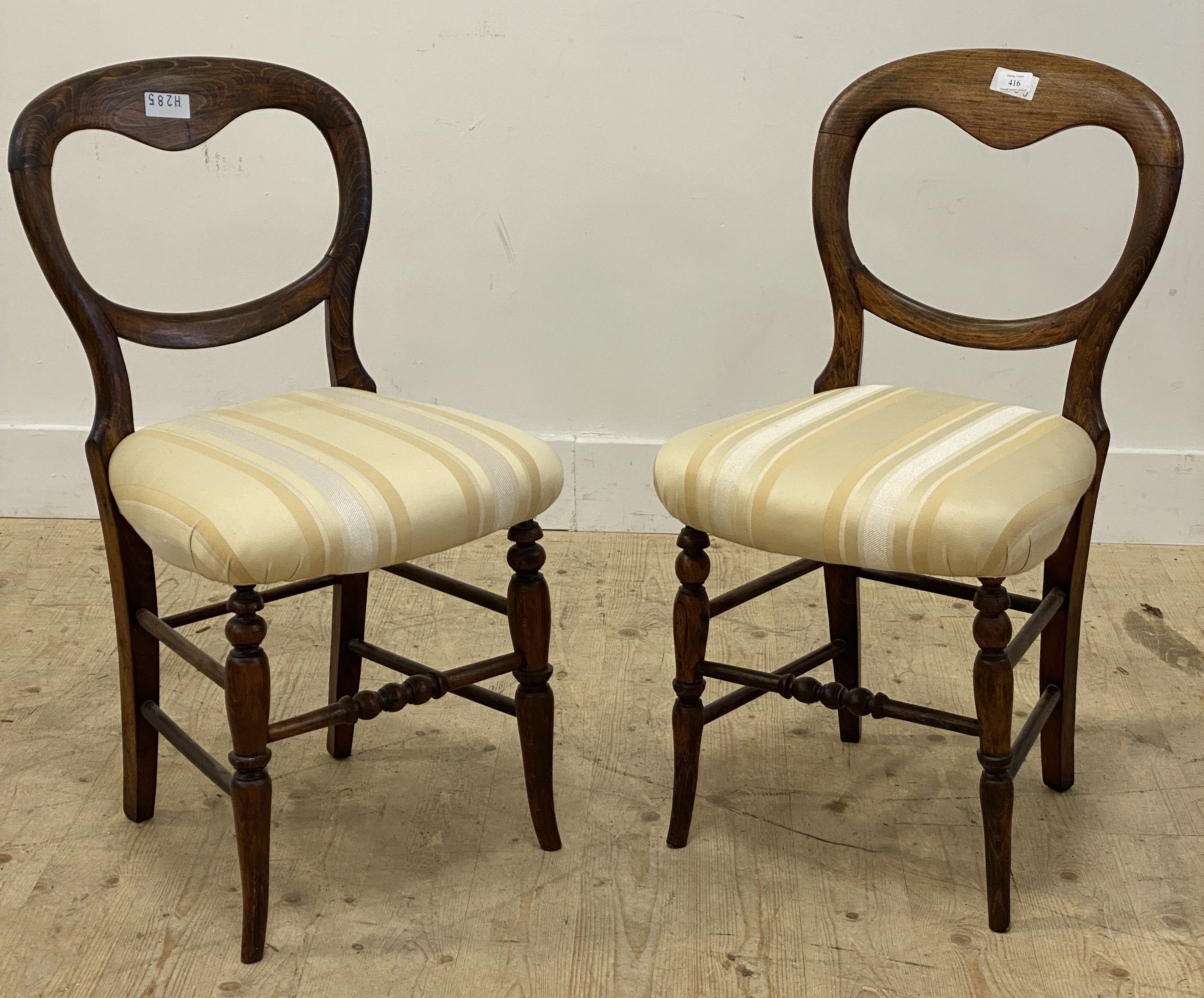 A pair of Victorian stained wood balloon back dining chairs, each with upholstered seats and