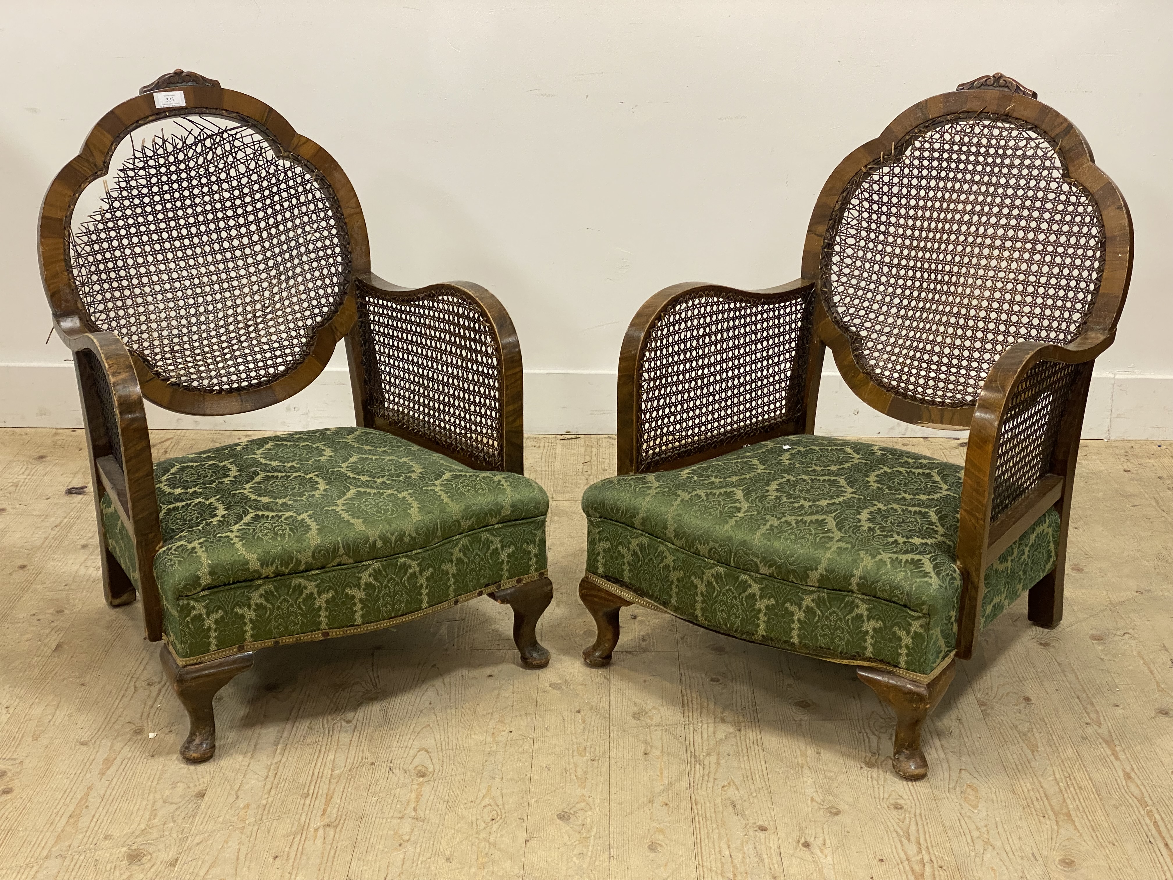 A pair of 1930's walnut framed bergere chairs, each with cane panelled back and sides, raised on