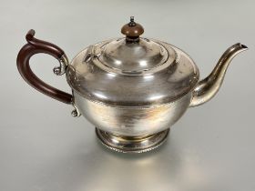 A Birmingham silver tea pot of circular form with beaded edge with stained wood knop and C scroll
