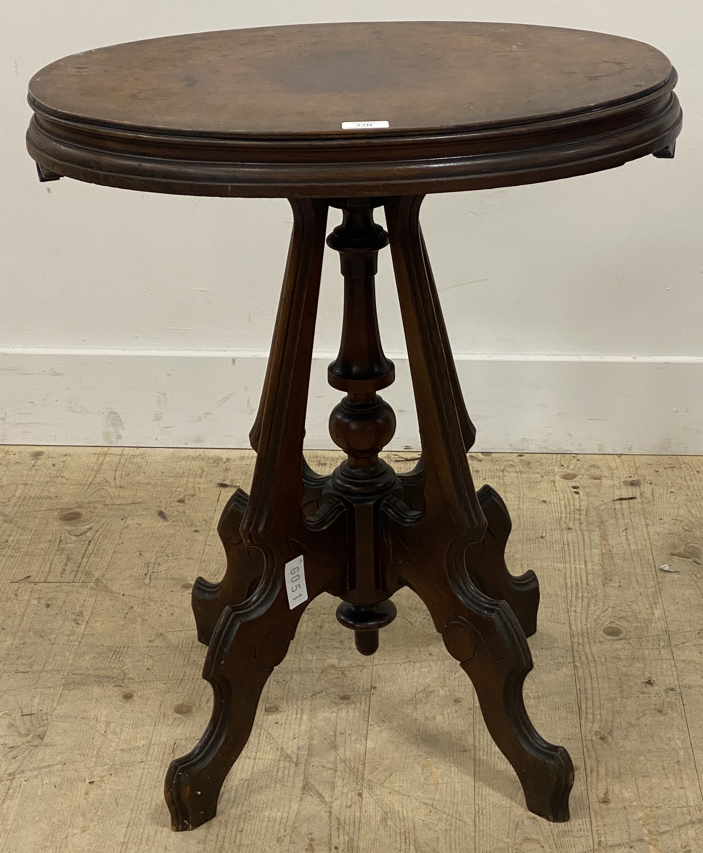 A late Victorian walnut occasional table, the oval top raised on four scroll carved and incised
