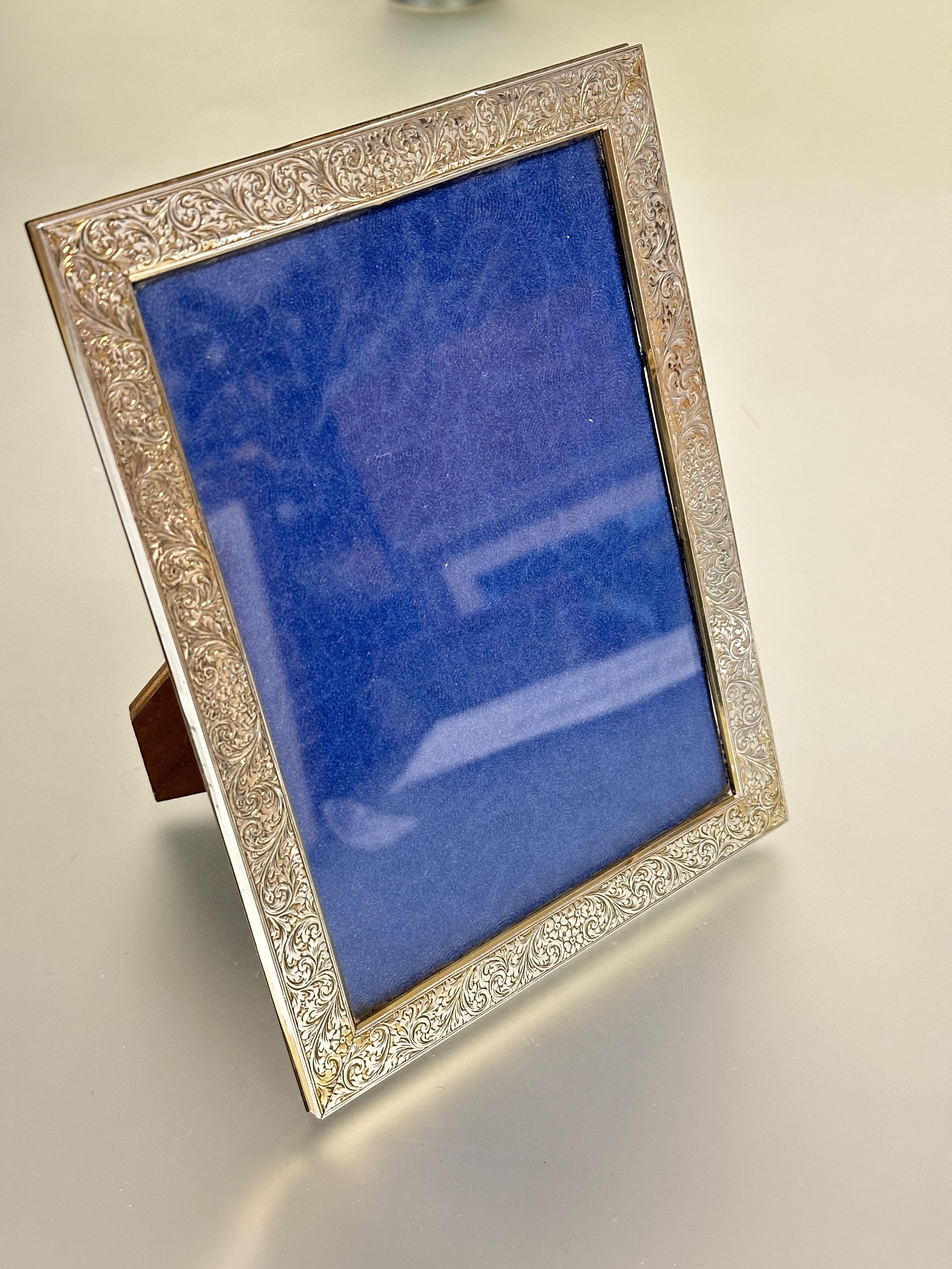 A 1920s silver rectangular photograph frame with chased scrolling acanthus leaf design and early