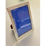 A 1920s silver rectangular photograph frame with chased scrolling acanthus leaf design and early