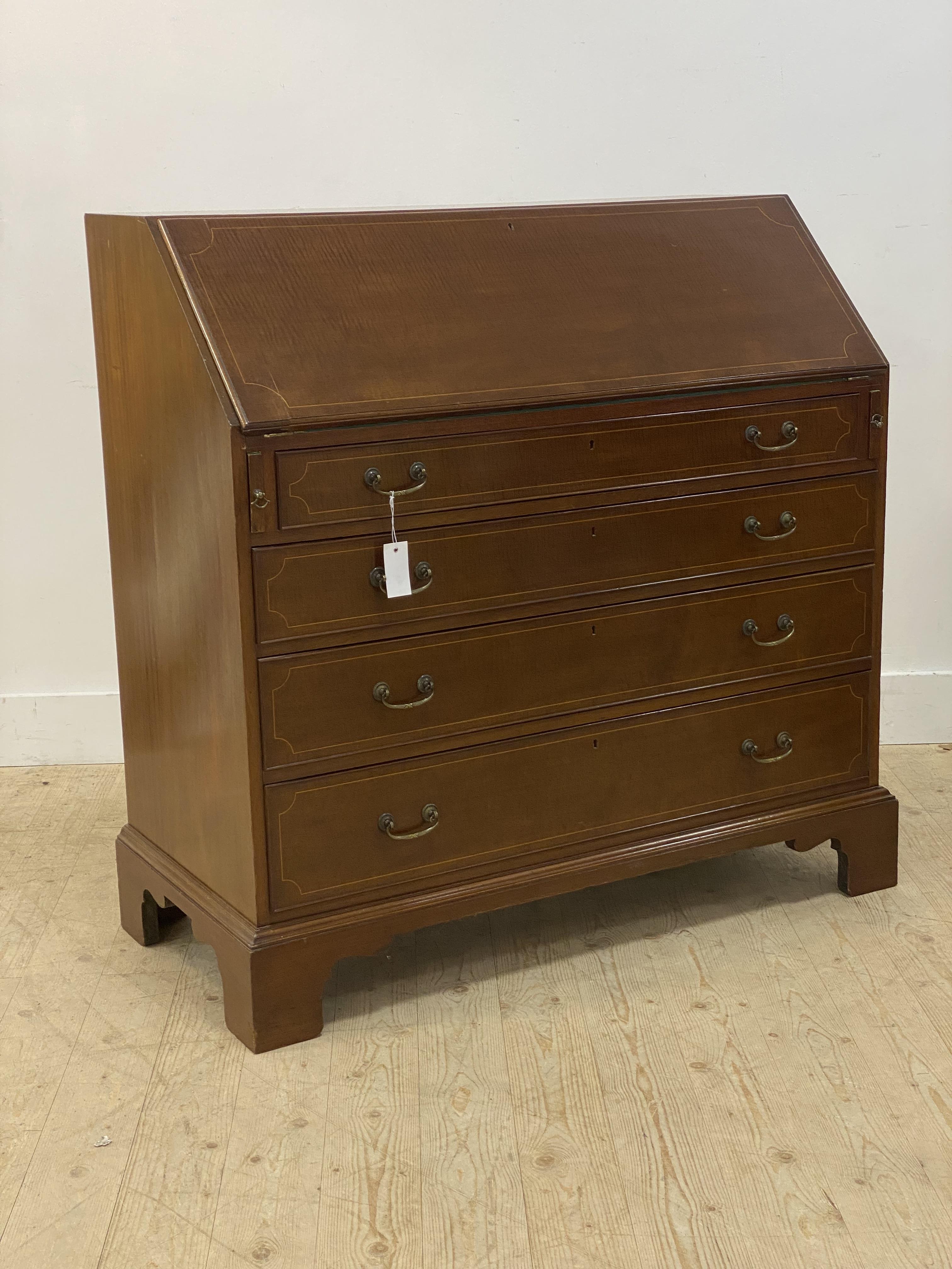 An Edwardian box wood strung mahogany bureau, the fall front opening to a fitted interior, above